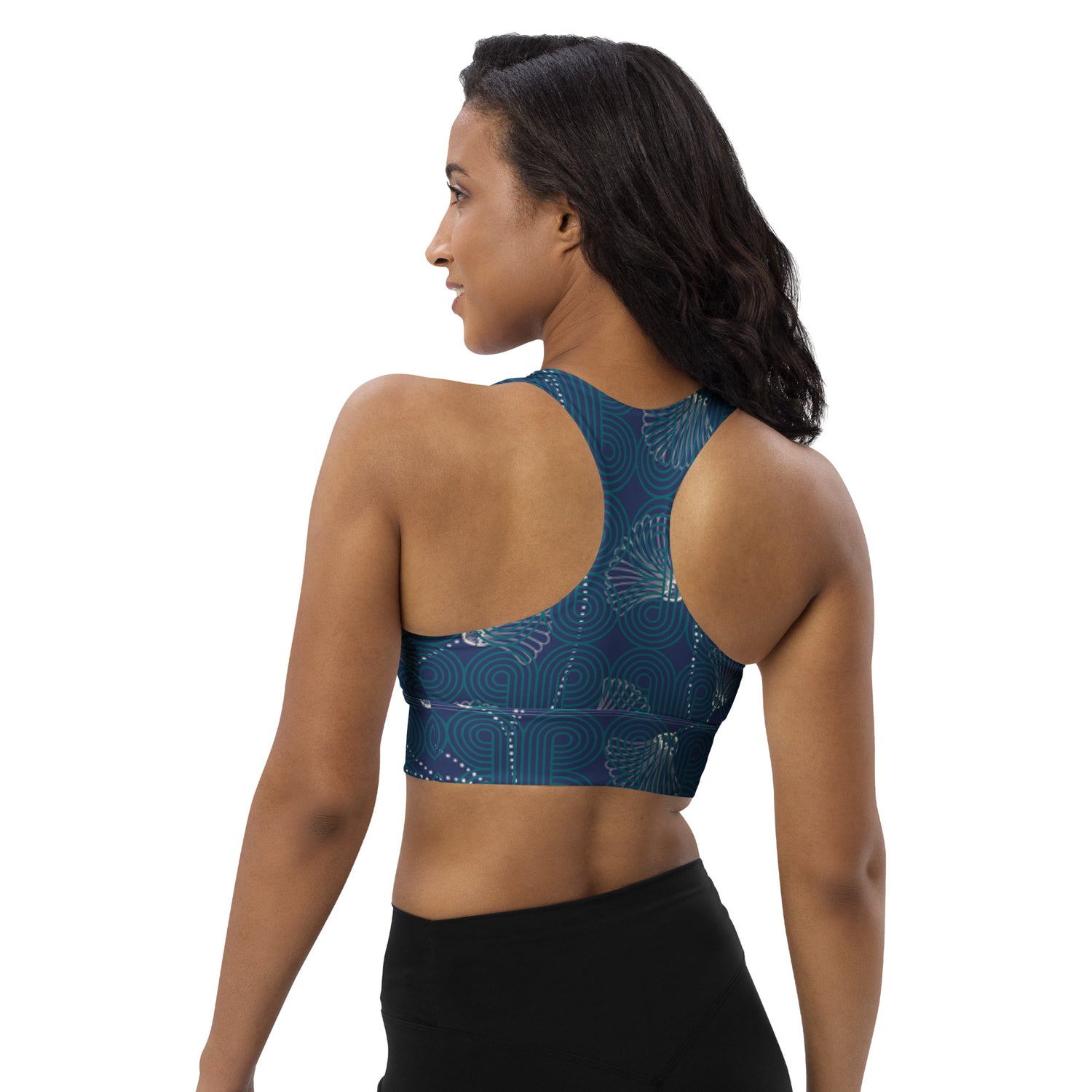 Woman wearing a blue patterned sports bra showing the back view and black leggings on a white background