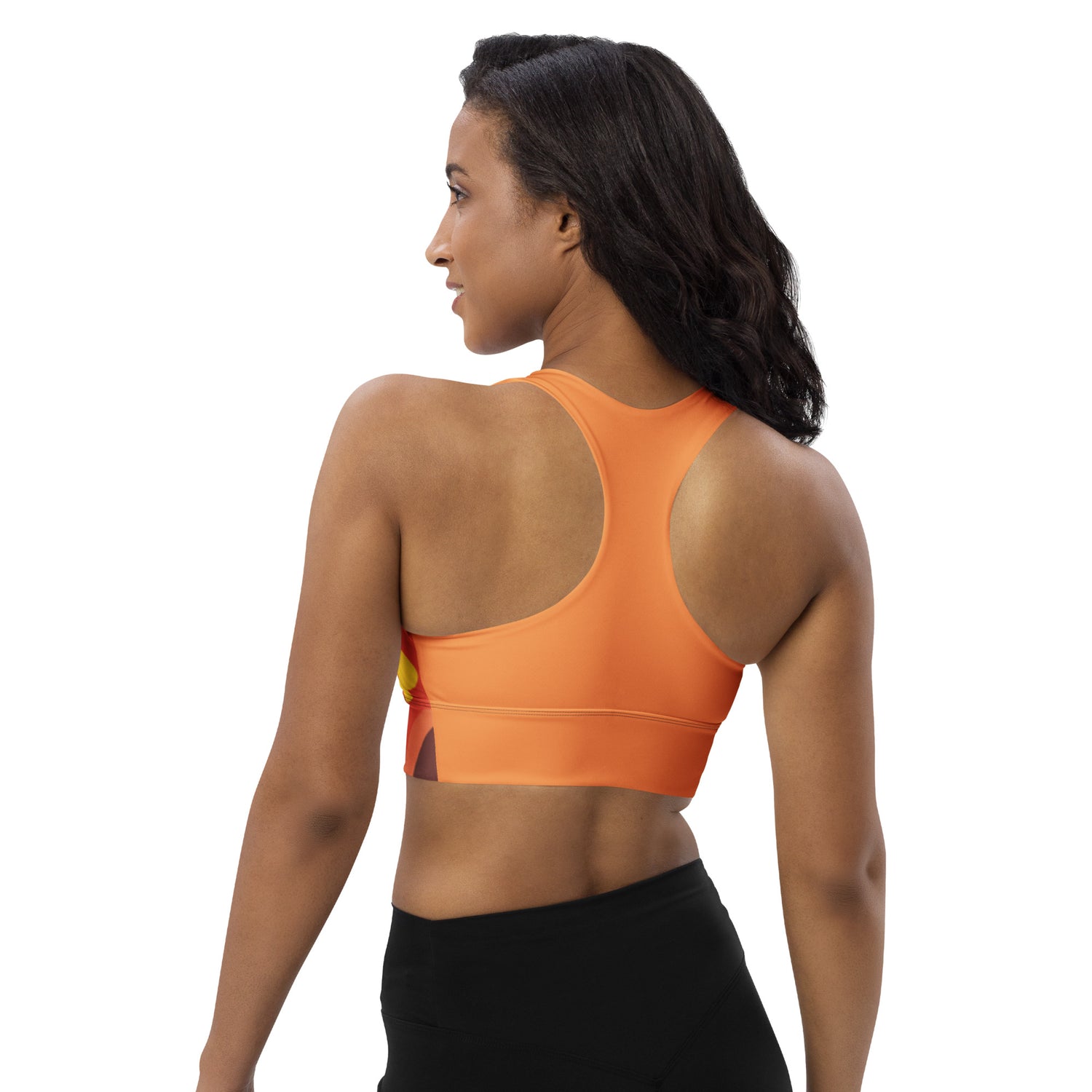 Woman wearing an orange sports bra and black leggings on a white background