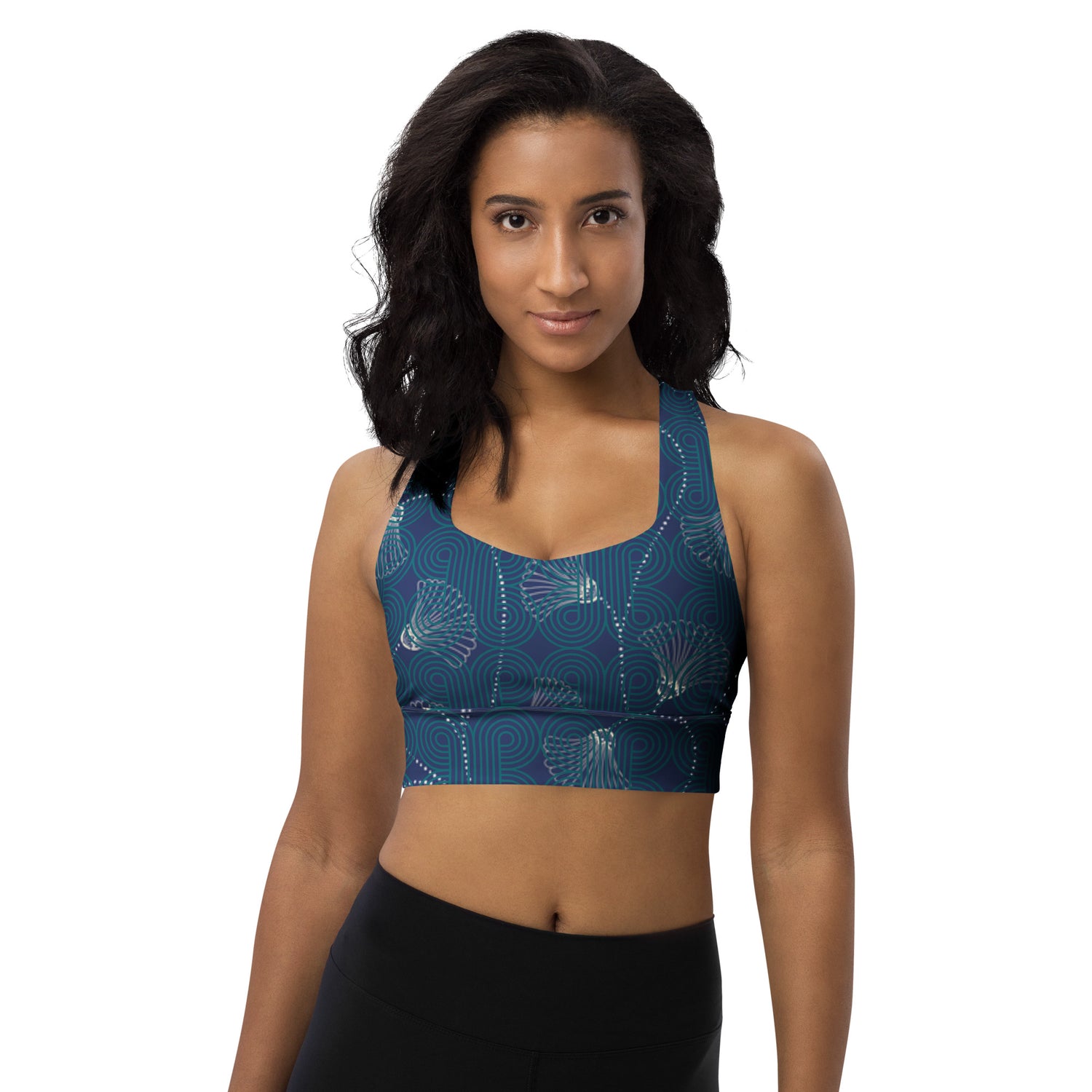 Woman wearing a blue patterned sports bra and black leggings on a white background