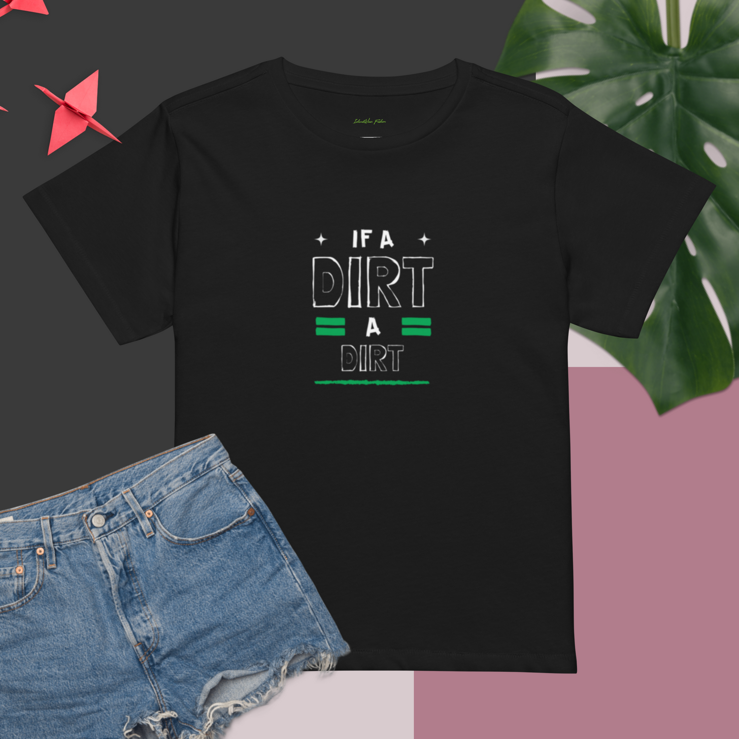 Black t-shirt featuring the graphic "If A Dirt, A Dirt" Jamaican Slang in white and green text. Shirt is styled with denim shorts and a tropical leaf | IslandWear Fashion 