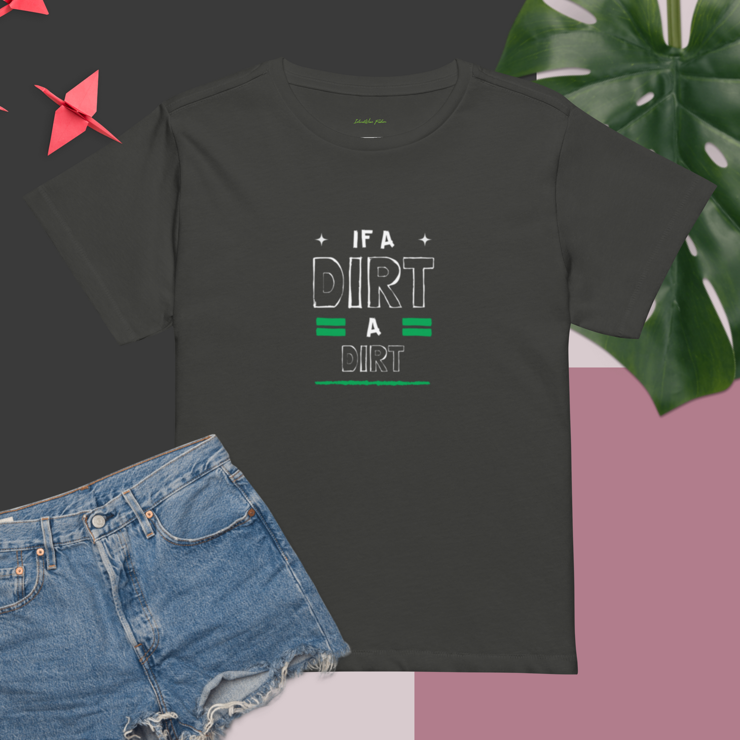 Vintage black / grey t-shirt featuring the graphic "If A Dirt, A Dirt" Jamaican  slang white and green text. Shirt is styled with denim shorts and a tropical leaf | IslandWear Fashion 